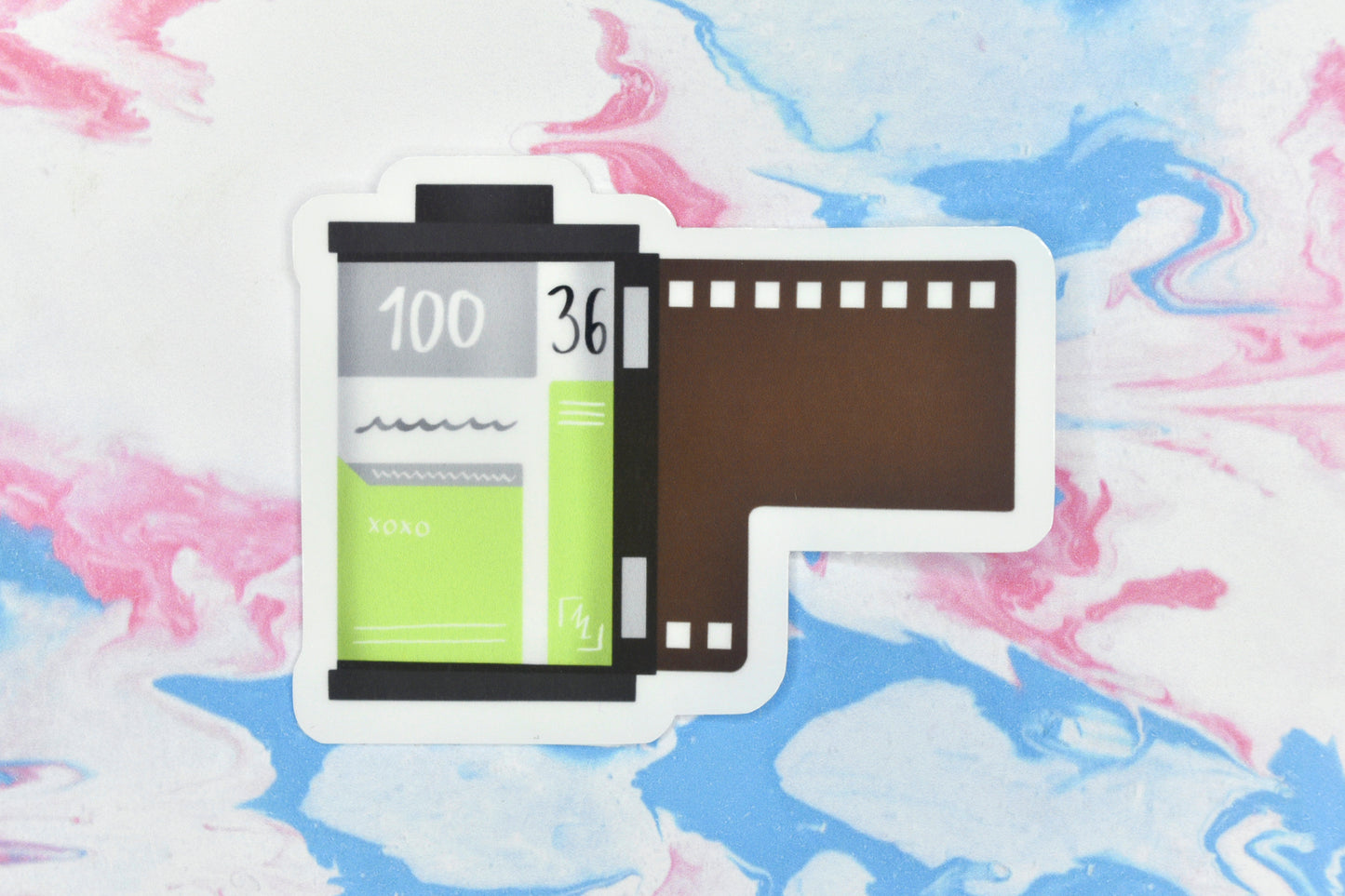 An LGBTQ+ pride vinyl sticker depicting a roll of film in the agender pride flag colours.