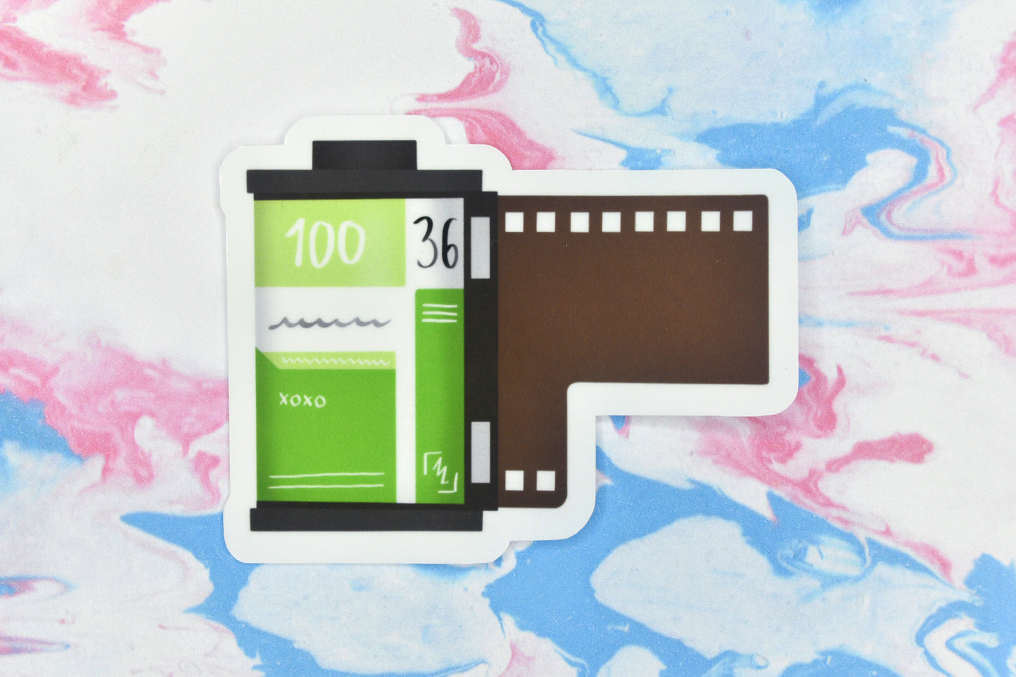 An LGBTQ+ pride vinyl sticker depicting a roll of film in the aromantic pride flag colours.