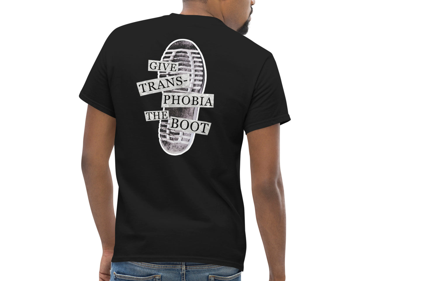 A mock-up of the back of a black t-shirt worn by a model. The back of the t-shirt features a photograph of the bottom of a black combat boot. There is text overlaid on the photograph in a paper collage style which reads "give transphobia the boot".
