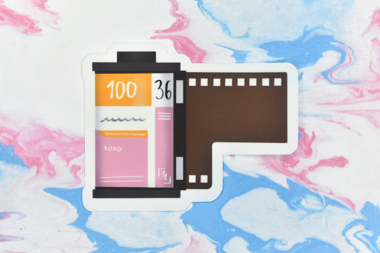 An LGBTQ+ pride vinyl sticker depicting a roll of film in the lesbian pride flag colours.