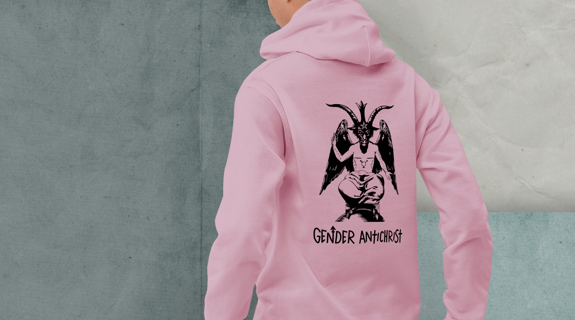 A model is pictured from the back wearing a pink hoodie with a black print on the back which features an illustration of Baphomet with top surgery scars, a trans symbol tattoo on their torso and the words "queer" and "liberation" tattooed on their right and left arms respectively. Below Baphomet is text reading "Gender Antichrist".