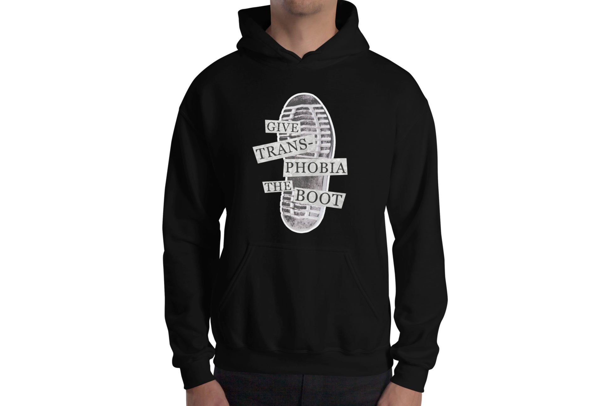 A mock-up of a black hoodie worn by a model. The hoodie features a photograph of the bottom of a black combat boot. There is text overlaid on the photograph in a paper collage style which reads "give transphobia the boot".