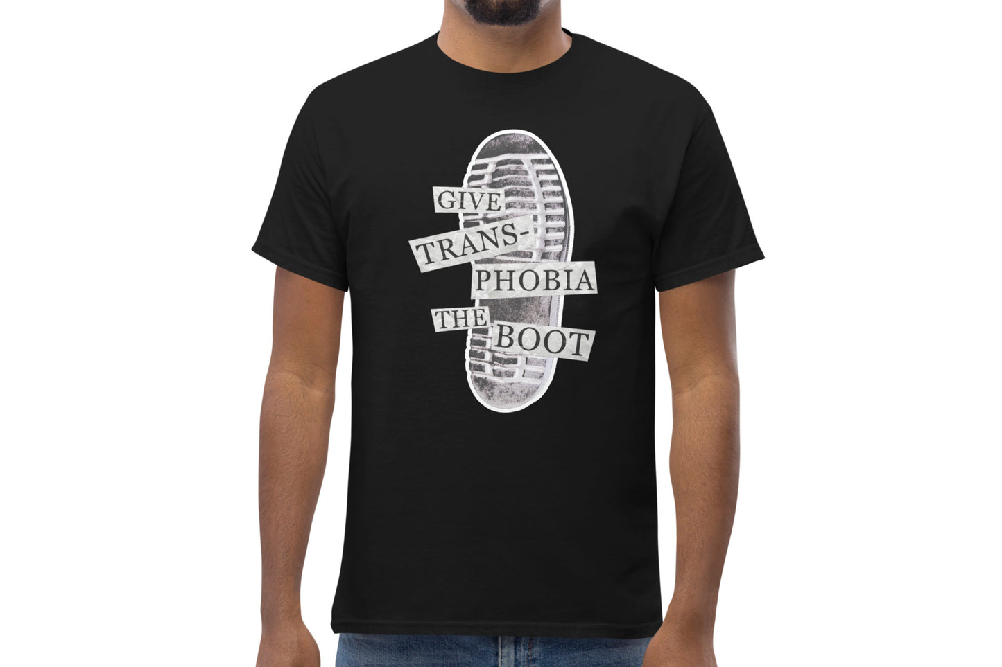 A mock-up of a black t-shirt worn by a model. The t-shirt features a photograph of the bottom of a black combat boot. There is text overlaid on the photograph in a paper collage style which reads "give transphobia the boot".