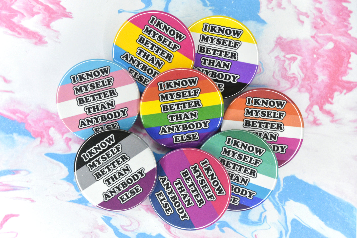 A collection of eight badges each with a different pride flag background and black and white text in a bubble-like font reading "I know myself better than anybody else". The pride flags shown are trans, pansexual, non-binary, rainbow, lesbian, asexual, bisexual and MLM.