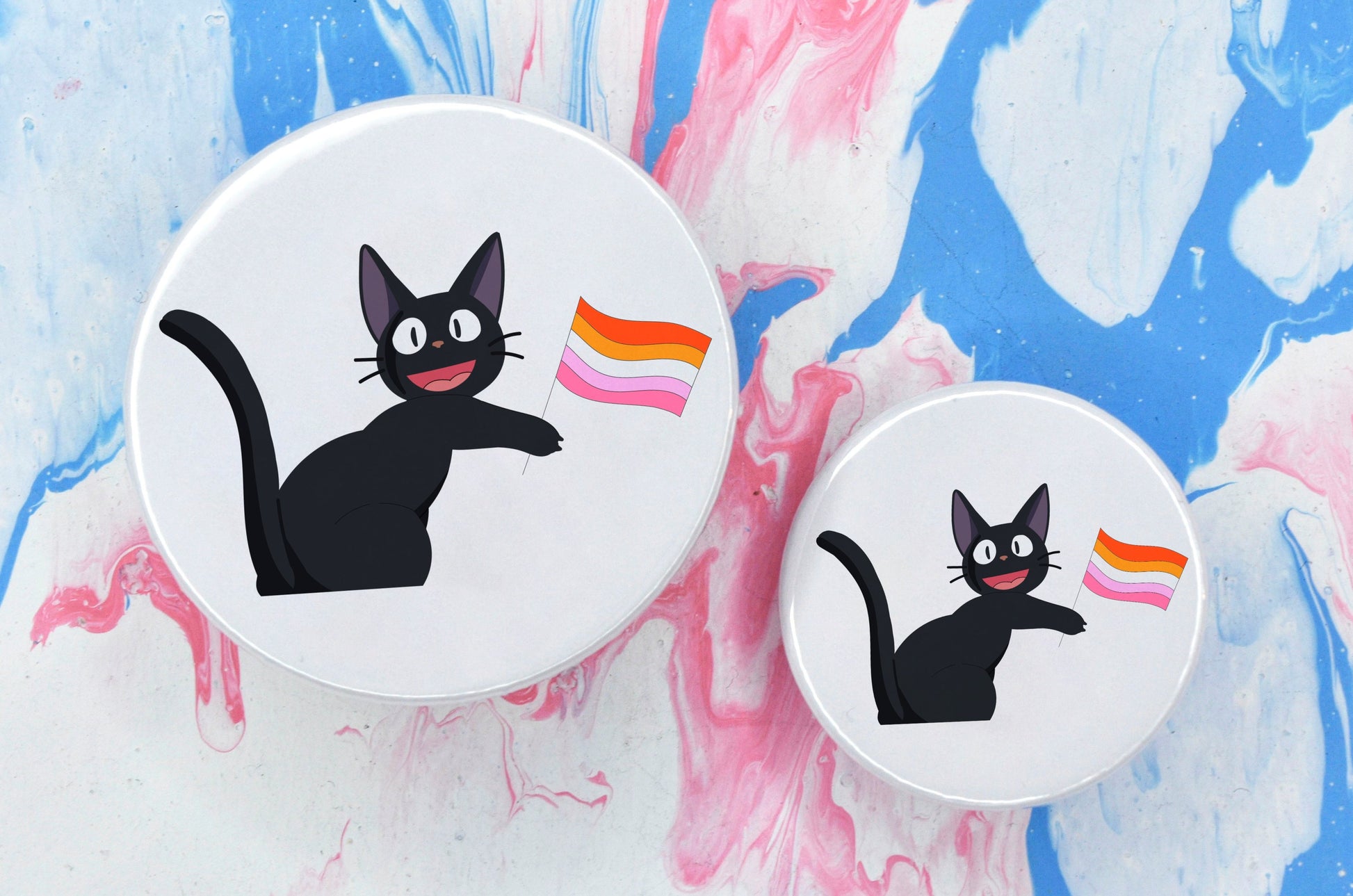 Two pin badges in sizes medium and small, both featuring an illustration of a black anime-style cat holding a lesbian pride flag. The background of the badge is white.