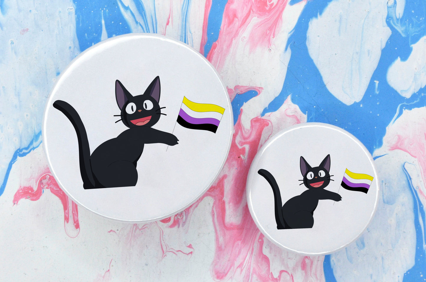 Two pin badges in sizes medium and small, both featuring an illustration of a black anime-style cat holding a non-binary pride flag. The background of the badge is white.